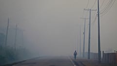  Eine Person geht auf der Autobahn BR-319 durch den Rauch eines Waldbrandes, der 2023 Careiro Castanho im brasilianischen Bundesstaat Amazonas erreicht.