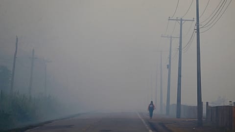  Una persona cammina sull'autostrada BR-319 tra il fumo di un incendio boschivo che raggiunge Careiro Castanho, nello stato brasiliano di Amazonas, nel 2023.