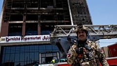 Un guardia de seguridad iraquí frente a un centro comercial incendiado en Kut, 17 de julio de 2025.