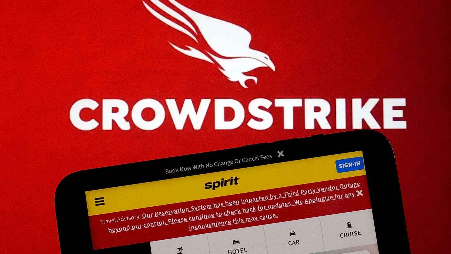 The logo for CrowdStrike and a Spirit Airlines webpage are shown on a computer screen and mobile phone screen, in New York, Friday, July 19, 2024
