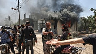 مقاتلون بدو يتجمعون أمام متجر محترق في قرية المزرعة على مشارف مدينة السويداء 18 يوليو 2025