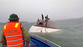 Esta imagem de um vídeo fornecido pela QDND mostra pessoas num barco turístico virado a serem resgatadas na Baía de Ha Long,