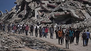 فلسطينيون يحملون أكياسًا من المساعدات الإنسانية التي تم تفريغها من قافلة الشاحنات التي كانت متجهة إلى مدينة غزة