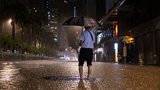 أحد المشاة ينتظر حافلة في شارع غمرته المياه بعد عواصف مطيرة غزيرة في هونغ كونغ, يوم الجمعة,سبتمبر. 8, 2023.