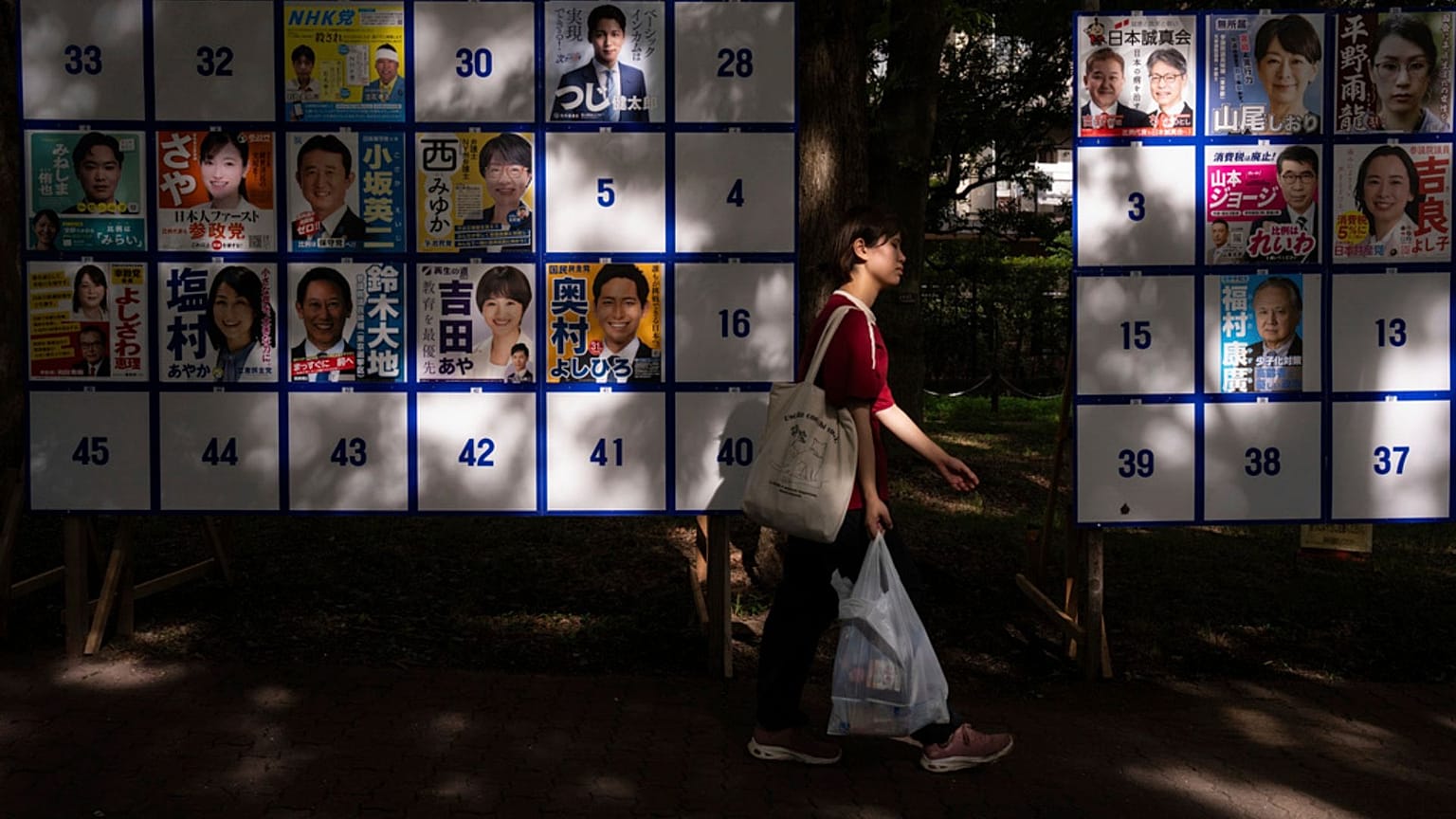 Un peatón pasa junto a un tablón electoral que muestra carteles de candidatos para las próximas elecciones a la Cámara Alta del 20 de julio en Tokio, 18 de julio de 2025.