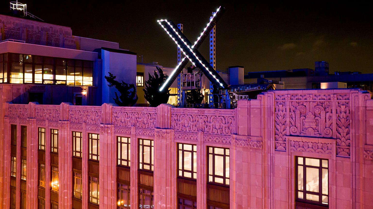 Workers install lighting on an "X" sign atop the company headquarters, formerly known as Twitter, in downtown San Francisco, on Friday, July 28, 2023.