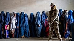 Ein Taliban-Kämpfer steht Wache, während Frauen darauf warten, Lebensmittelrationen zu erhalten, die von einer humanitären Hilfsorganisation in Kabul verteilt werden, 23. Mai 2023
