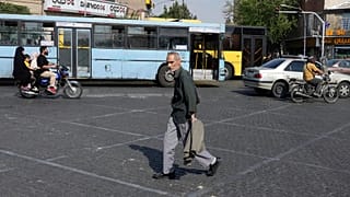 Tahran şehir merkezinde bir adam karşıdan karşıya geçerken, 21 Temmuz 2025