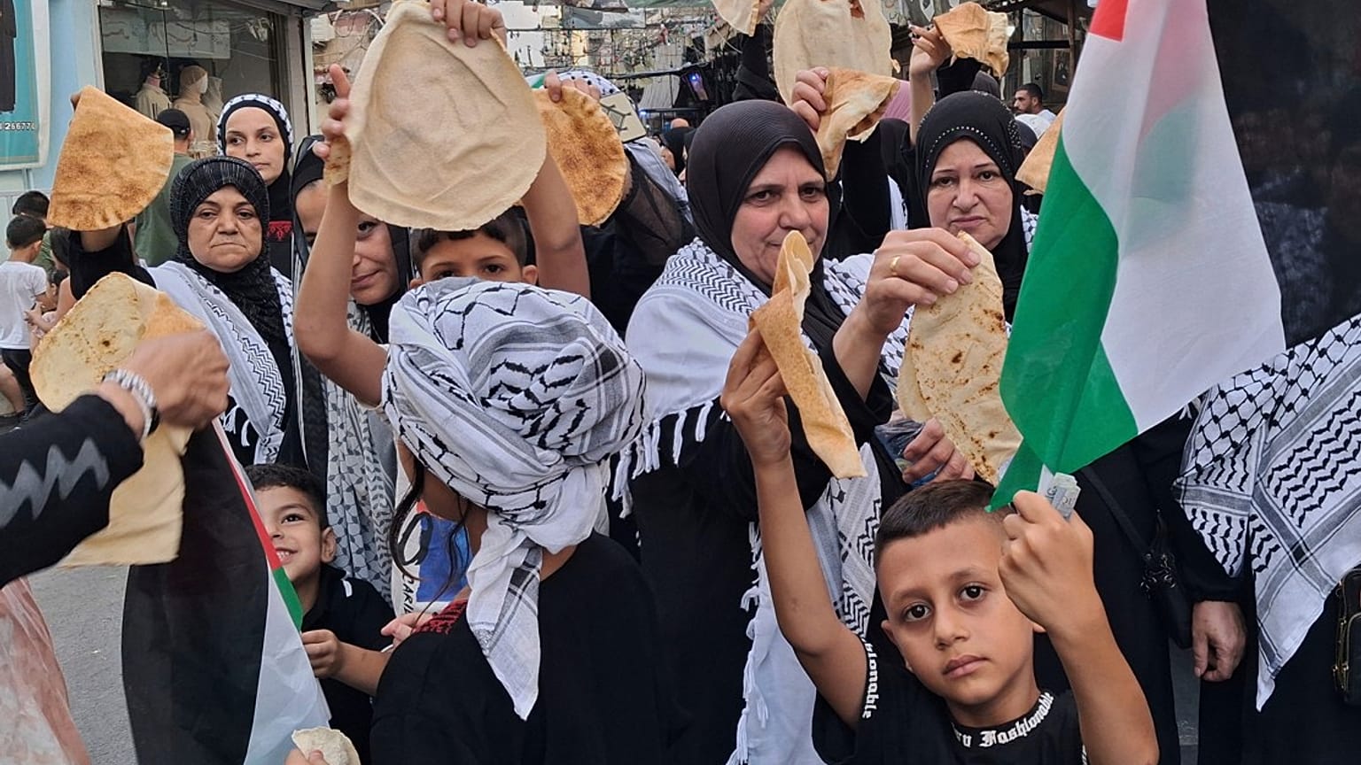 فلسطينيون يحملون قطعًا من الخبز خلال احتجاج في مخيم عين الحلوة للاجئين في مدينة صيدا الساحلية الجنوبية بلبنان، الأحد 20 يوليو/تموز 2025. 