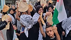 فلسطينيون يحملون قطعًا من الخبز خلال احتجاج في مخيم عين الحلوة للاجئين في مدينة صيدا الساحلية الجنوبية بلبنان، الأحد 20 يوليو/تموز 2025. 