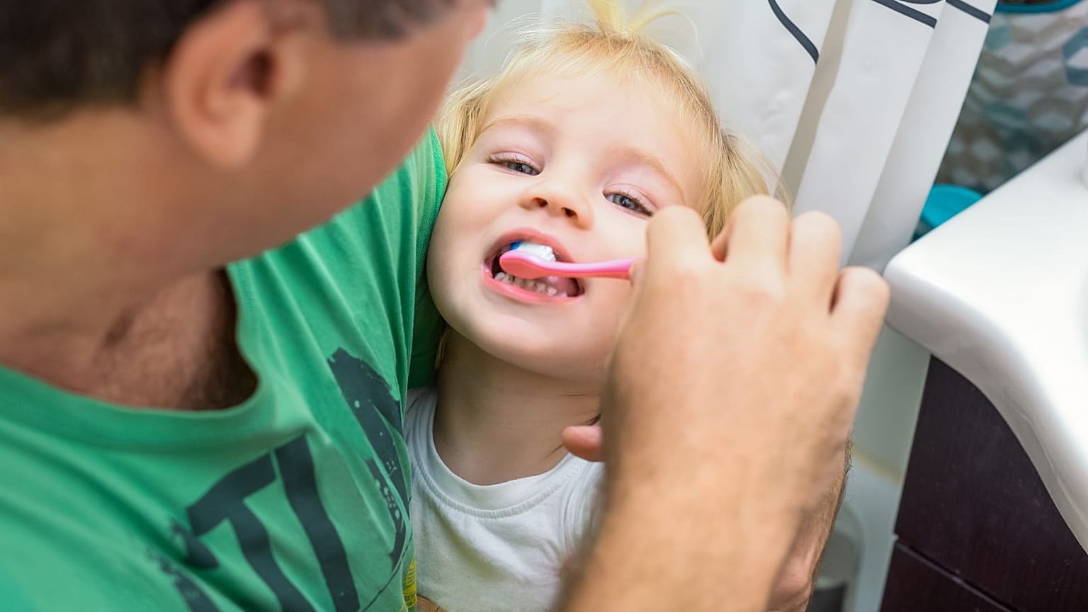 A parent brushes their child's teeth.