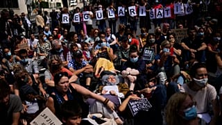 People listen to speeches during a protest in support of migrants without officials papers on hunger strike in Brussels, 17 July, 2021