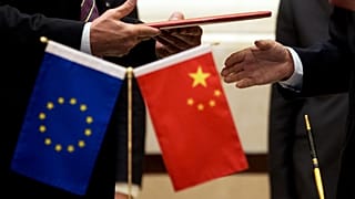 Um membro da Comissão Europeia, à esquerda, prepara-se para trocar documentos com uma delegação chinesa numa cerimónia de assinatura