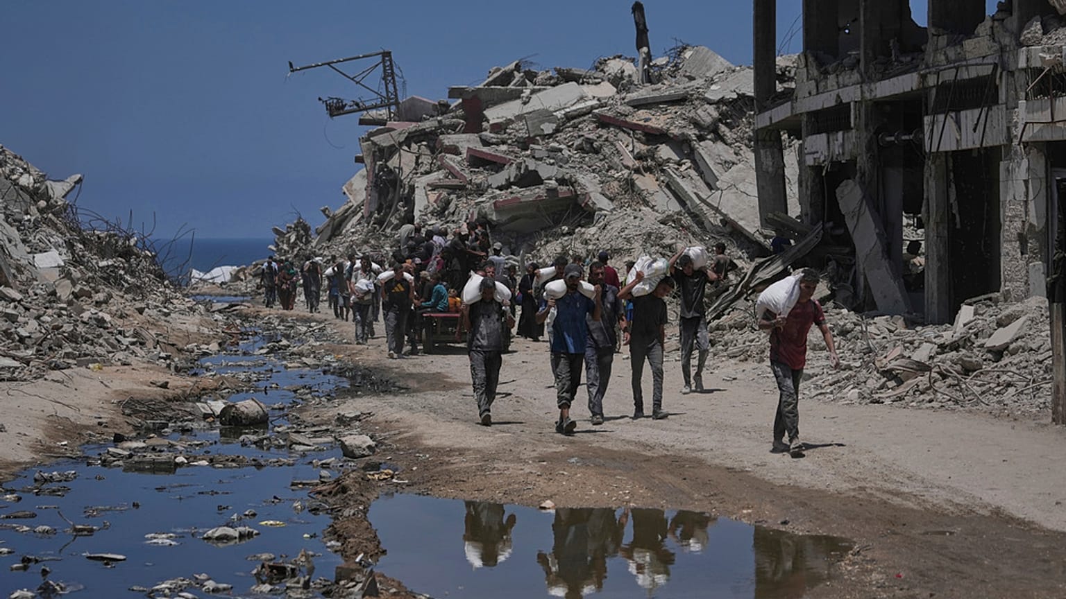 فلسطينيون يحملون أكياس الدقيق التي تم تفريغها من قافلة مساعدات إنسانية وصلت إلى مدينة غزة من شمال قطاع غزة