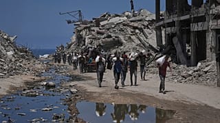 Palestinianos carregam sacos de farinha descarregados de um comboio de ajuda humanitária que chegou à Cidade de Gaza vindo do norte da Faixa de Gaza