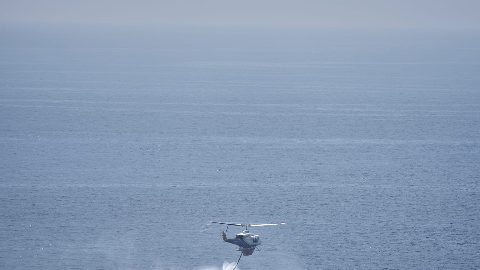 Helikopter pobiera wodę z morza w Lavrio, około 60 kilometrów na południowy wschód od Aten.