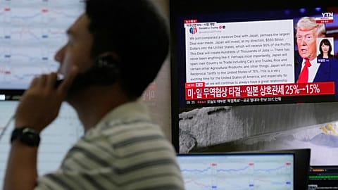 A currency trader works near the screen showing news reporting with a picture of President Donald Trump, in the Hana Bank headquarters in Seoul, South Korea, 23 July 2025.