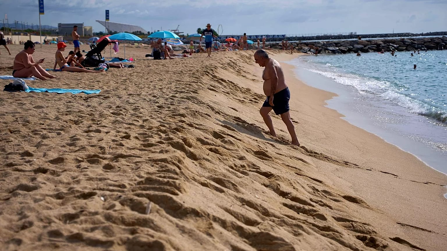 Un nuotatore cammina sulla riva di una spiaggia di Barcellona, in Spagna.