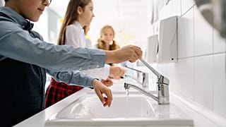 A group of children wash their hands.