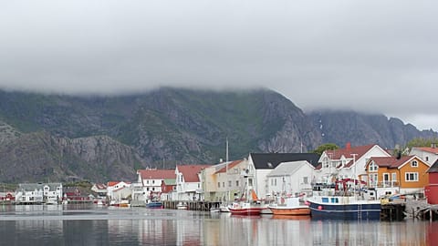 A Norwegian fishing village, hidden in the fjords, under a dense fog. 
