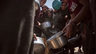 نازحون فلسطينيون يتلقون الطعام المتبرع به في مطبخ مجتمعي في مدينة غزة، شمال قطاع غزة، الثلاثاء 22 يوليو/تموز 2025.