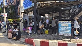 Varias personas sentadas cerca de un puesto de control fronterizo entre Tailandia y Camboya en la provincia de Sa Kaeo, 24 de junio de 2025.