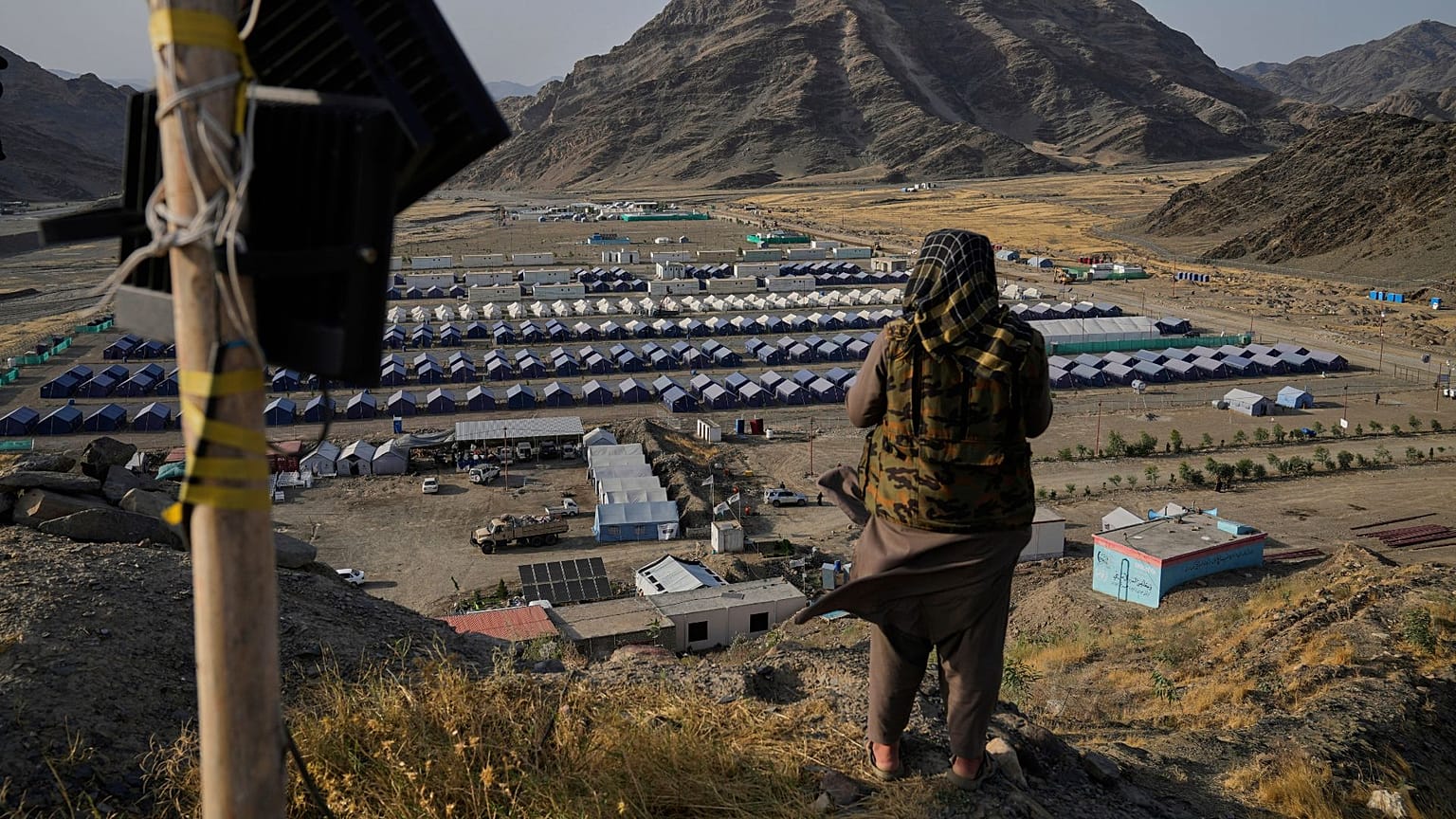  یک عضو طالبان در ۳۱ مه ۲۰۲۵، در گذرگاه مرزی تورخم، افغانستان، مشرف به اردوگاه پناهندگان افغانِ بازگردانده شده از پاکستان 