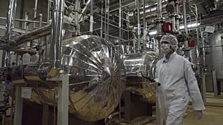 Egy iráni biztonsági tisztviselő védőruhában sétál az uránátalakító létesítmény egy részén Iszfahán városának külterületén, 2005. március 30-án