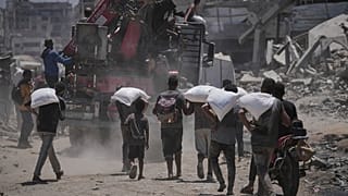 فلسطينيون يحملون أكياس طحين حصلوا عليها من قافلة مساعدات إنسانية وصلت إلى مدينة غزة، الثلاثاء 22 يوليو 2025.