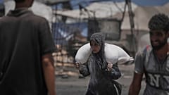 فلسطينيون يحملون أكياس الدقيق التي تم تفريغها من قافلة مساعدات إنسانية وصلت إلى مدينة غزة من شمال قطاع غزة، الثلاثاء 22 يوليو 2025. 