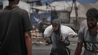 فلسطينيون يحملون أكياس الدقيق التي تم تفريغها من قافلة مساعدات إنسانية وصلت إلى مدينة غزة من شمال قطاع غزة، الثلاثاء 22 يوليو 2025. 