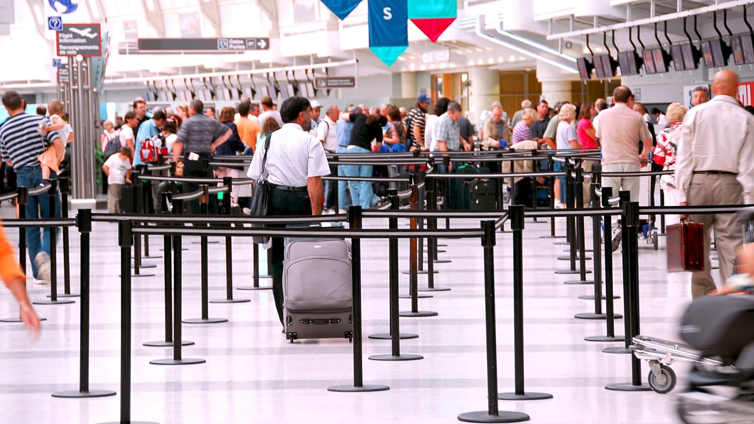 Bir havalimanındaki check-in kontuarlarında sıra bekleyen yolcular. 