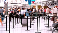 Fluggäste, die in der Schlange vor den Check-in-Schaltern eines Flughafens warten. 