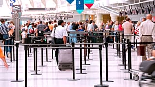 Passageiros em fila de espera nos balcões de check-in de um aeroporto.