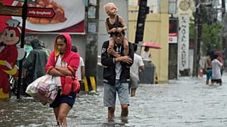 سكان يسيرون في شارع غمرته المياه بفعل أمطار غزيرة في مدينة مالابون شمال الفلبين، الخميس 24 يوليو 2025.