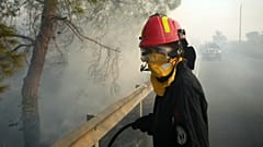 A firefighter, along with her colleagues, tries to extinguish a fire in Souni village on the southern side of Cyprus' Troodos mountain range, 24 July 2025