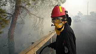 A firefighter, along with her colleagues, tries to extinguish a fire in Souni village on the southern side of Cyprus' Troodos mountain range, 24 July 2025
