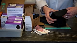 Uma farmacêutica prepara uma roupa interior para a menstruação ao lado de outros artigos gratuitos, numa farmácia em Barcelona, Espanha, terça-feira, 5 de março de 2024. 