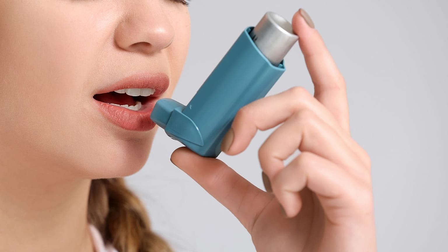A woman uses an inhaler.