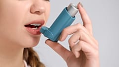 A woman uses an inhaler.