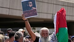 مشارك في استقبال جورج عبد الله يرفع صورته في مطار بيروت الدولي، 25 يوليو/ تموز 2025.