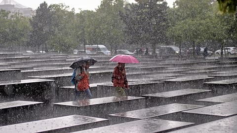 Two visitors walk through the Holocaust Memorial in heavy rain in Berlin, Germany, Thursday, 5 June 2025
