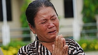 Une villageoise pleure en faisant don de ses effets personnels aux forces armées de première ligne sur un trottoir du district de Srey Snam, dans la province de Siem Reap, au Cambodge, samedi.