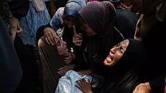 Maysara Adwan, solda, İsrail'in Gazze'de sığınak olarak kullanılan bir okula düzenlediği hava saldırısında ölen 11 yaşındaki oğlu Qais'in cesedini tutarken yas tutuyor.