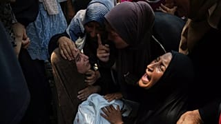 Maysara Adwan, à esquerda, chora enquanto segura o corpo do seu filho de 11 anos, Qais, que foi morto num ataque aéreo israelita a uma escola em Gaza que tem sido usada como abrigo, durante