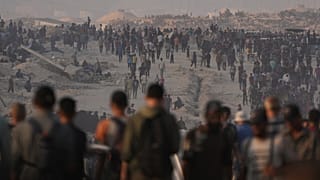 Palestinians walk along a road toward an area in the northern Gaza Strip where trucks are entering with humanitarian aid, in Gaza City, 26 July 2025