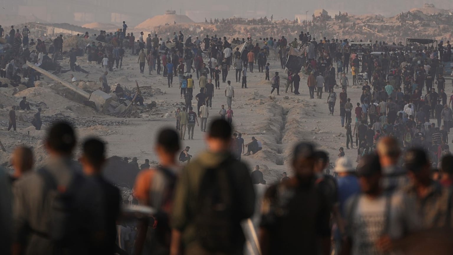 فلسطينيون يسيرون على طول الطريق المؤدي إلى منطقة في شمال قطاع غزة حيث تدخل الشاحنات المحملة بالمساعدات الإنسانية، في مدينة غزة، الجمعة 25 يوليو/تموز 2025. 