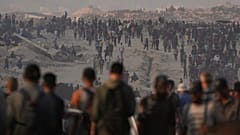 فلسطينيون يسيرون على طول الطريق المؤدي إلى منطقة في شمال قطاع غزة حيث تدخل الشاحنات المحملة بالمساعدات الإنسانية، في مدينة غزة، الجمعة 25 يوليو/تموز 2025. 