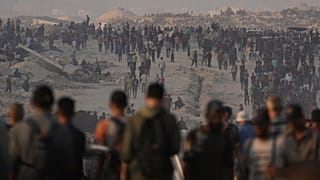 فلسطينيون يسيرون على طول الطريق المؤدي إلى منطقة في شمال قطاع غزة حيث تدخل الشاحنات المحملة بالمساعدات الإنسانية، في مدينة غزة، الجمعة 25 يوليو/تموز 2025. 
