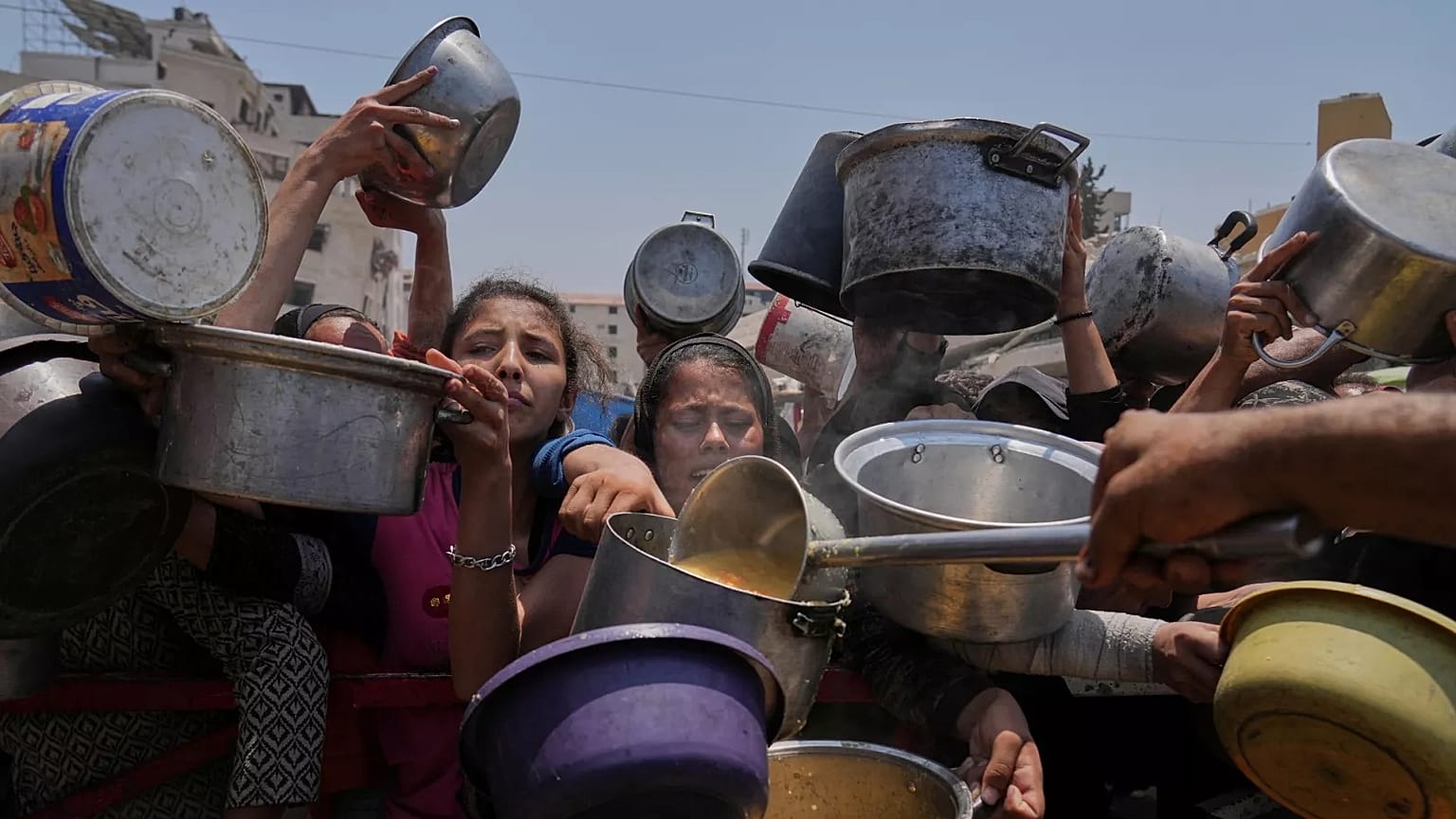 Os palestinianos lutam para obter alimentos doados numa cozinha comunitária, na Cidade de Gaza, no norte da Faixa de Gaza, sábado, 26 de julho de 2025. (AP Photo/Abdel Kareem Hana)